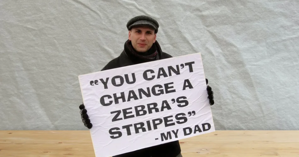 Peterson Toscano standing holding a sign that says "You can't change a zebra's stripes"